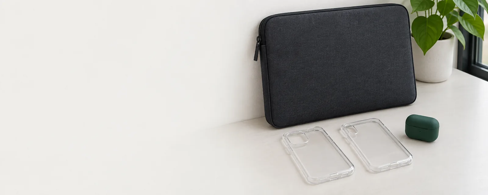 A laptop sleeve, phone cases and earbuds on a desk