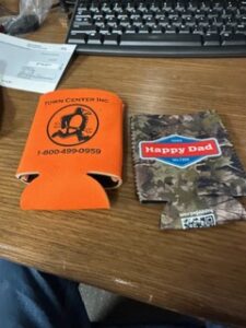 Printed can coolers and a camo koozie on a desk
