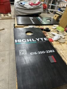 Black cornhole board with the Highlyte logo and phone number