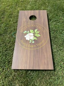 Wedding cornhole board with a floral crest on dark stain