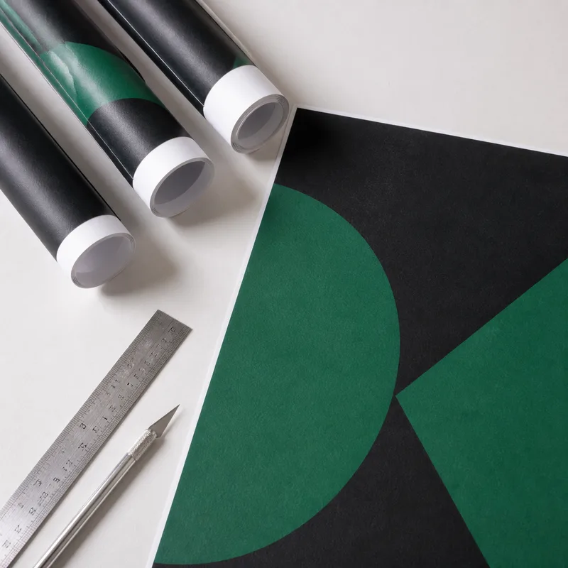 Rolled and flat matte poster prints on a worktable with a ruler and craft knife